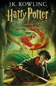 The cover of 'Harry Potter and the Chamber of Secrets' by J.K. Rowling, featuring Harry Potter holding a wand in front of a large snake and a phoenix in a mysterious, magical setting.