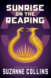 Book cover of 'Sunrise on the Reaping' by Suzanne Collins featuring a gold emblem of two intertwined snakes against a purple background with stylized sun rays.